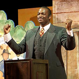 Actor portraying Martin Luther King at a podium onstage at the Palace Theater