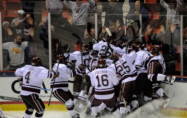 Hockey team celebrates game-winning goal in corner of the ice