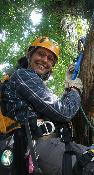 Catherine Cardelús climbing tree in harness and helmet