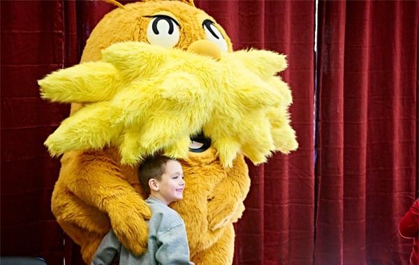 Child poses for a picture with a mascot of Dr. Seuss's Lorax