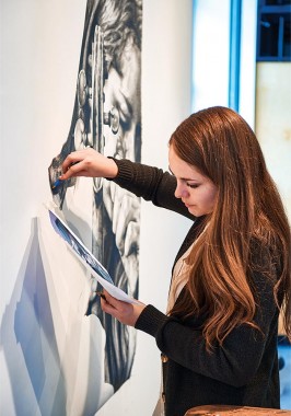 Deirdre Plaus '15 works on a portrait of herself tuning her violin.