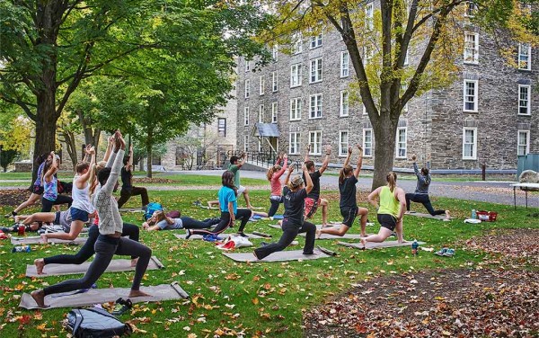 Yoga class in lunge position on the residential quad