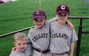 Three children in Colgate t-shirts and baseball caps on a staircase