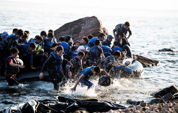 Refugees jumping into water from a precarious vessel near the beach