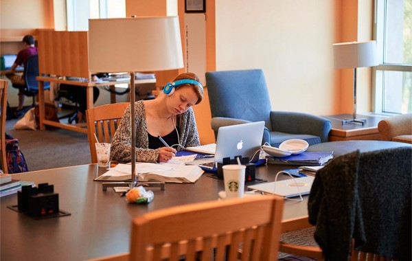 A student wears headphones while working in Case Library