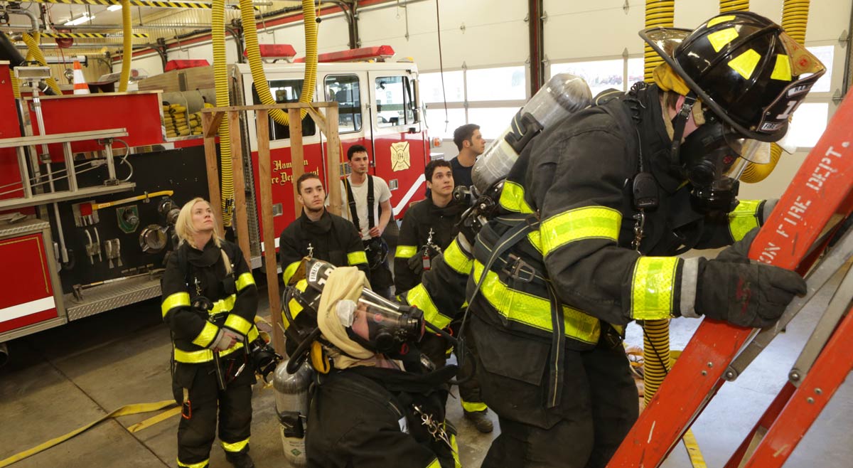Students in gear drill on a ladder at the station