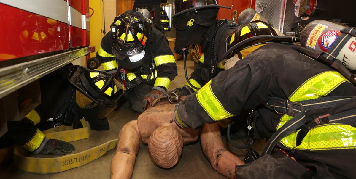 Firefighters drill on a dummy at the station