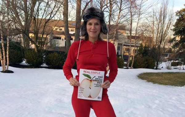 Lee McConaughy Woodruff '82 standing in the snow in red longjohns with an issue of Real Simple magazine