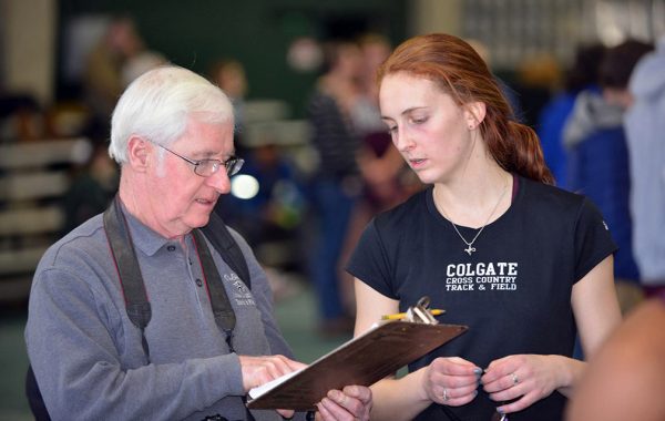 Cross country/track and field coach Arthur McKinnon consults a clipboard with an athlete