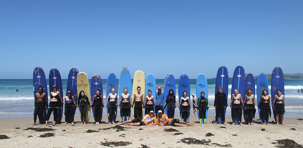 Students on the beach with surfboards in Wollongong, Australia