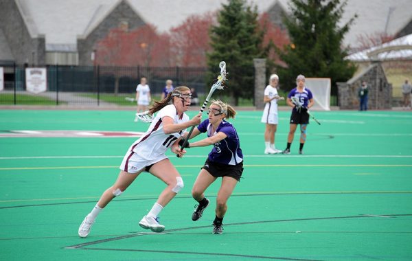 Courtney Miller ’12 runs with the ball by a defender in a lacrosse game at Colgate.