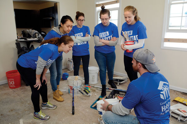 Colgate students huddle around for a lesson from a Habitat for Humanity volunteer