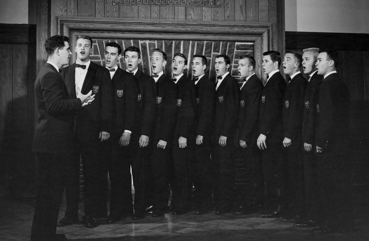 Archival photo of the Colgate 13 singing in the Hall of Presidents