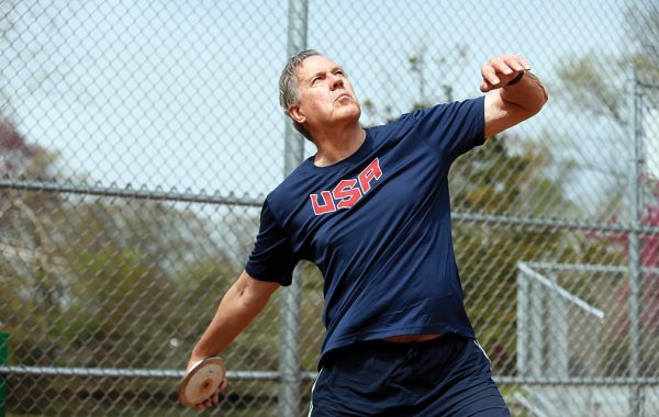 Roger Busch ’63 in a USA shirt throwing a discus
