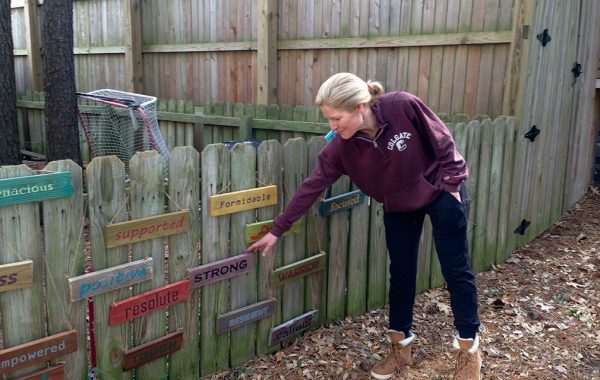 Brooke Baker Fox '93 standing next to signs of encouragement on her fence