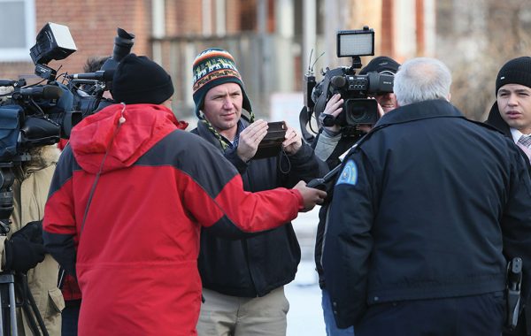Reporter Joel Currier ’00 records an outdoor interview with police