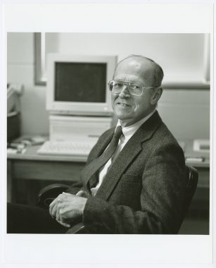 Black and white photo of James Howard Reynolds Jr. at a computer terminal