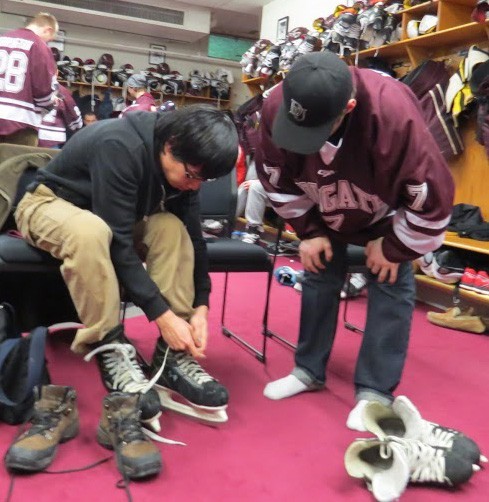 Ryan Johnston helps a Colgate student put his skates on prior to hitting the ice.