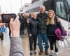 Two women's ice hockey players pause for a photo with a fan in front of the team bus