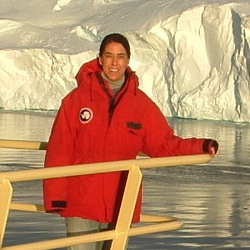 Portrait of Prof. Amy Leventer, standing on prow of boat in front of glacier