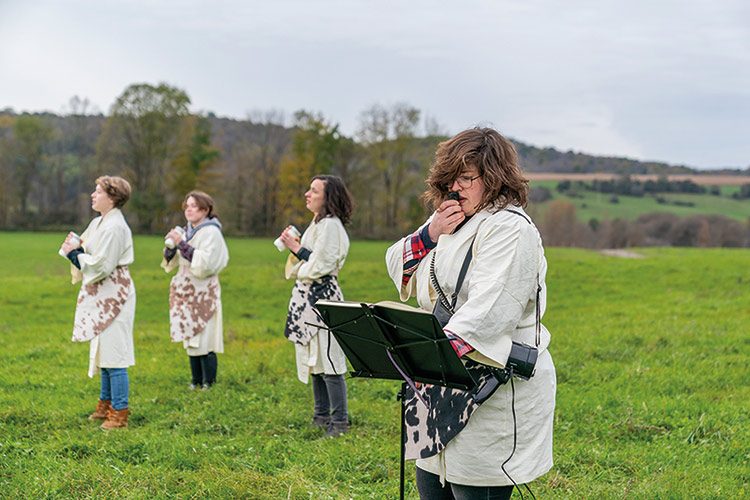 Jessica Posner and student artists in bathrobes in a field