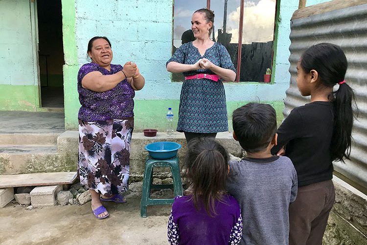 Two women lead children in hand-washing demonstration