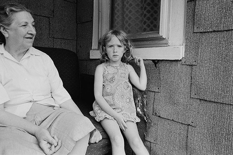 Black and White photo of old woman and girl on porch