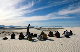 Professor speaking to students sitting in the desert