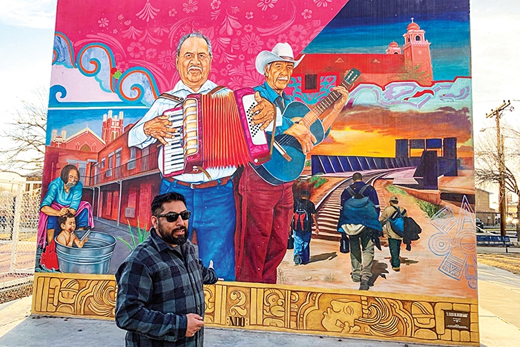 Muralist standing infront of mural of folk musicians