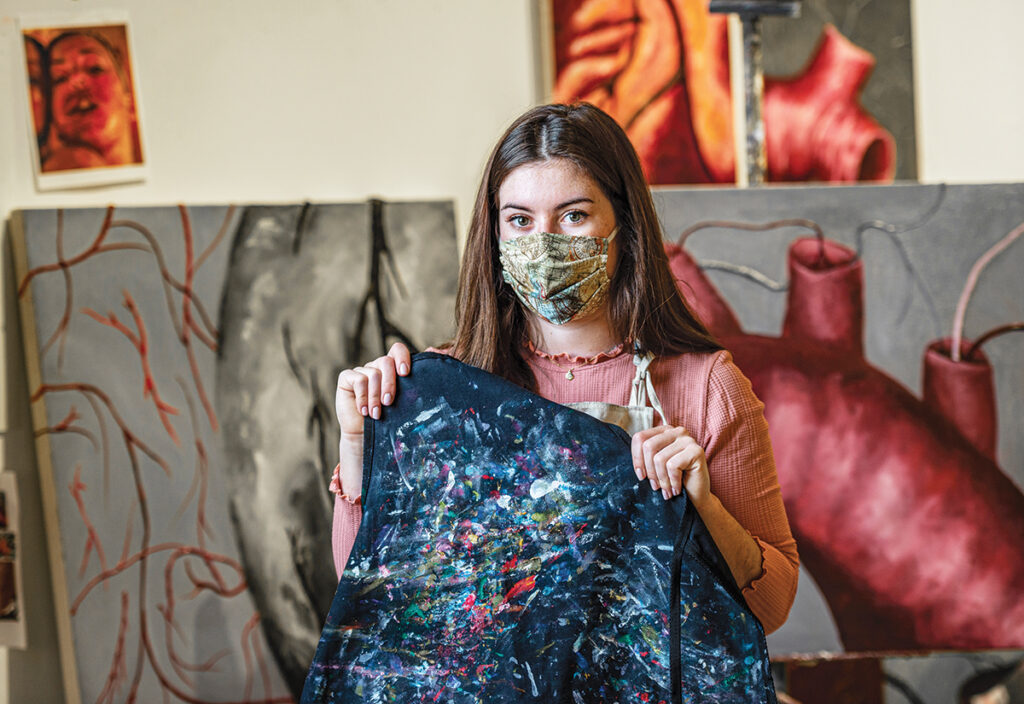  Allegra Knox ’21 holds her dad’s painting smock, which she displays on her wall as a reminder of him. 