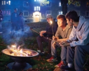 Three students roasting s'mores around a firepit