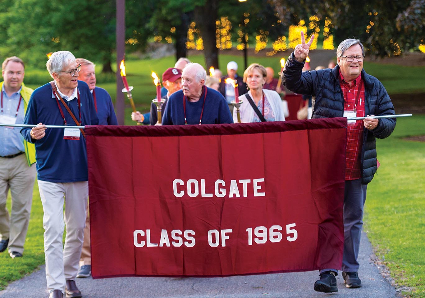 Group of alumni walk Willow Path while carrying the Class of 1965 banner