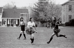 Black and white photo of three women playing lacrosse