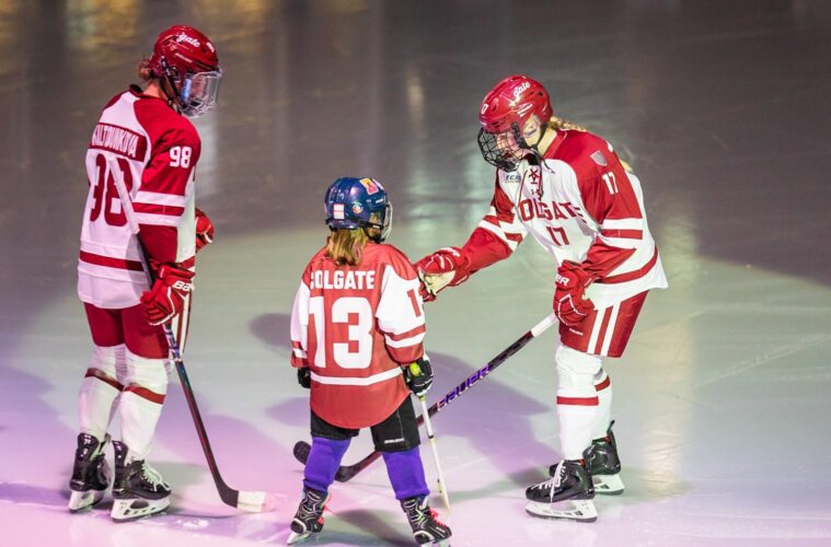 Two women's hockey players skate with a child