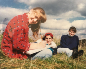 Three students sit in a grass field