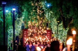 Colgate alumni hold lit torches as they walk through a lit Willow Path during Torchlight Ceremony.