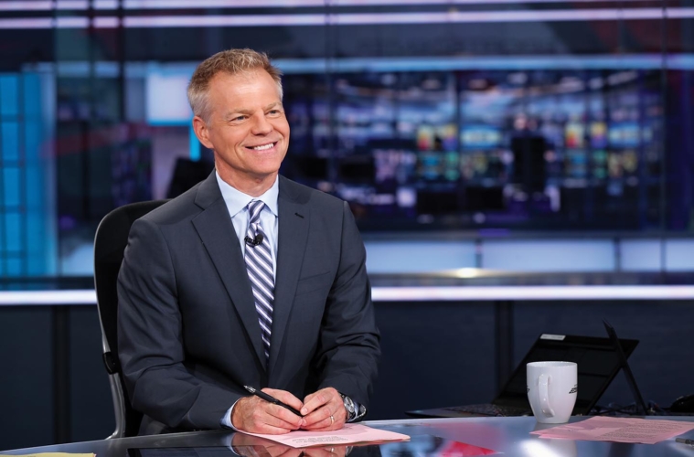 David Lloyd sits at a desk on the set of ESPN show Coast to Coast.