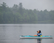 Student sits in a kayak with binoculars