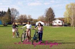 Three friends push their bikes through the grass