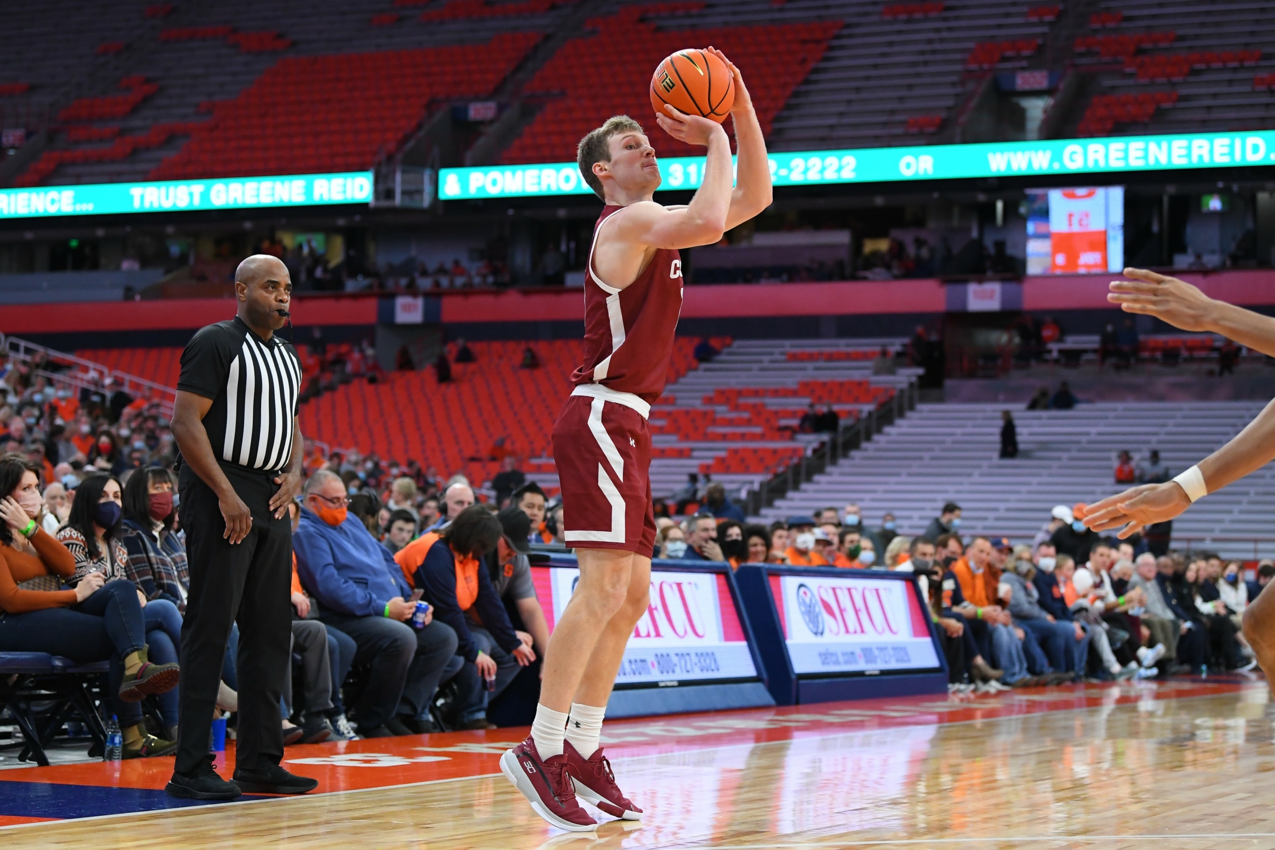 Colgate basketball player Tucker Richardson shoots a three pointer as fans watch the game.