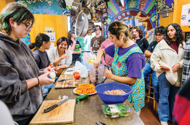 Elannah De La O is pictured-center, making sopa de albondigas as Colgate students gather around and watch.