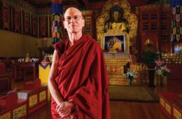 John Skeats ’73/Yonten Rabgye poses in Buddhist temple wearing crimson robes.