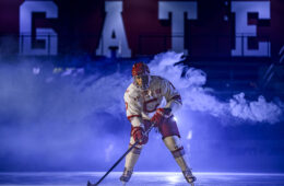 Ross Mitton in hockey uniform on ice with his hockey stick.