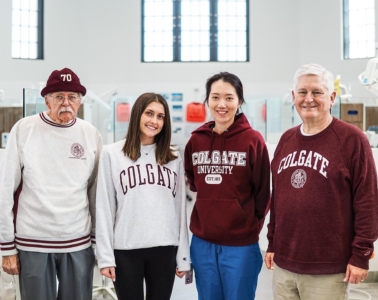 Group of alumni in Colgate attire stand together for a group photo