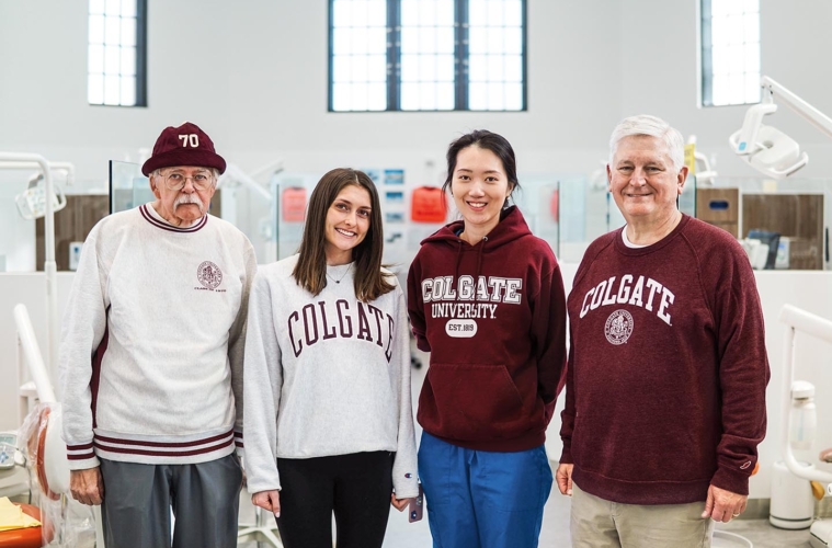Group of alumni in Colgate attire stand together for a group photo