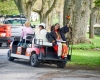 Student with flower bouquet and family riding a golf cart