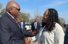 Laura Jack shakes hands with Congressman James Clyburn. Blue sky in the background.