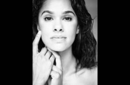 Black and white portrait of Misty Copeland. Her shoulder-length hair is down and her hands are tucked against the left side of her face