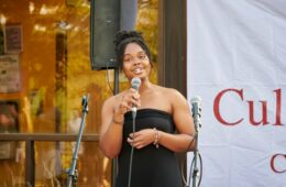 Student in a strapless black dress sings at a microphone