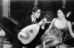 Rudolph Valentino plays a guitar for Nita Naldi on the set of the silent film Blood and Sand, 1922